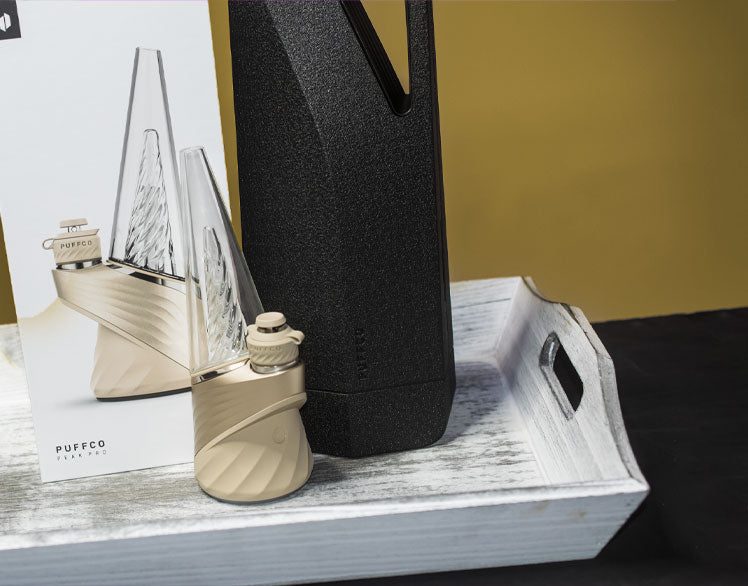 Puffco New Peak Pro Desert standing on white tray on black display with tan background