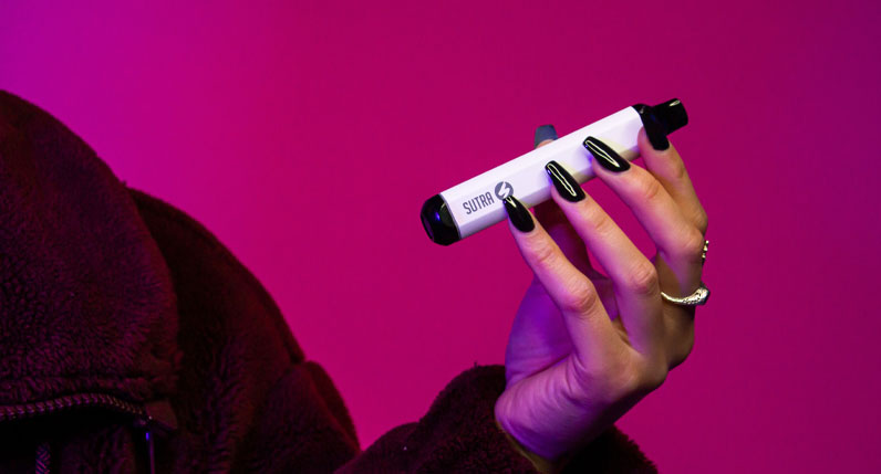 woman with coat holding the Sutra SILO inside studio with magenta background