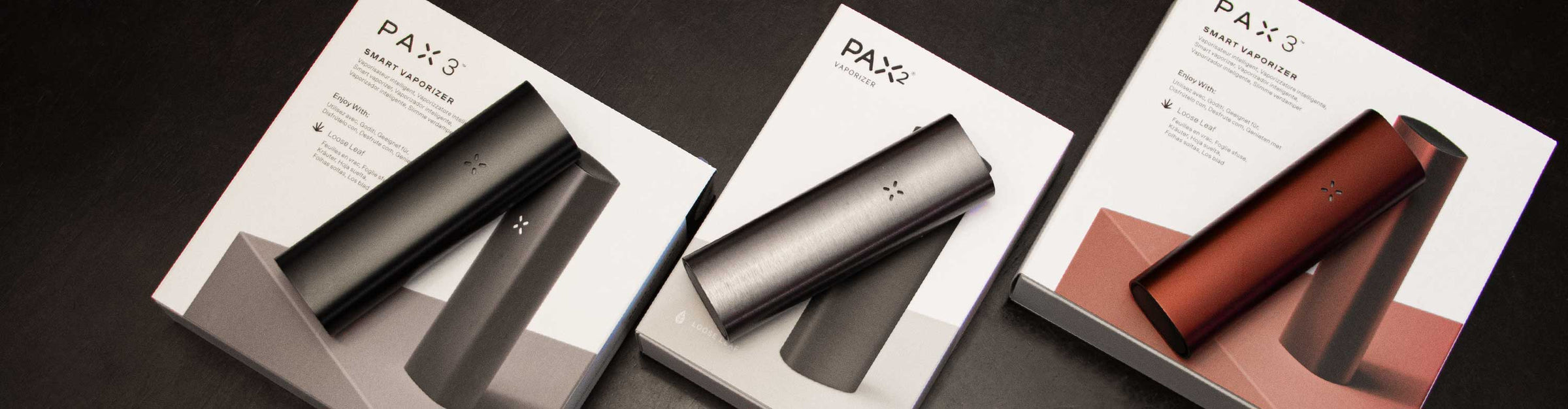 PAX vaporizers laying down with packaging on wooden dinner table.