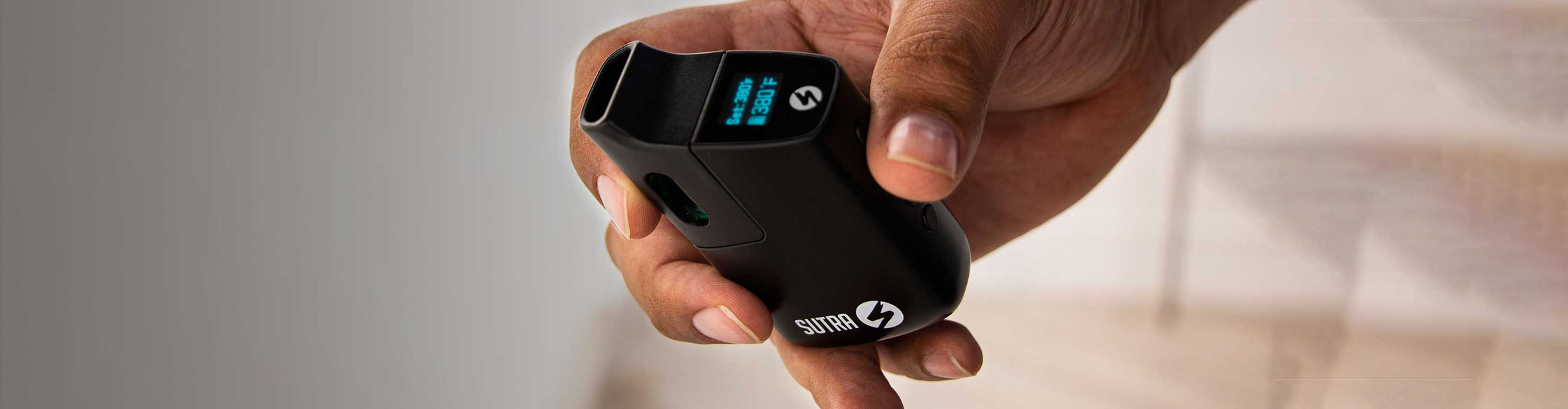 Man holding the Sutra Vape Mini at angle showing LED screen inside studio