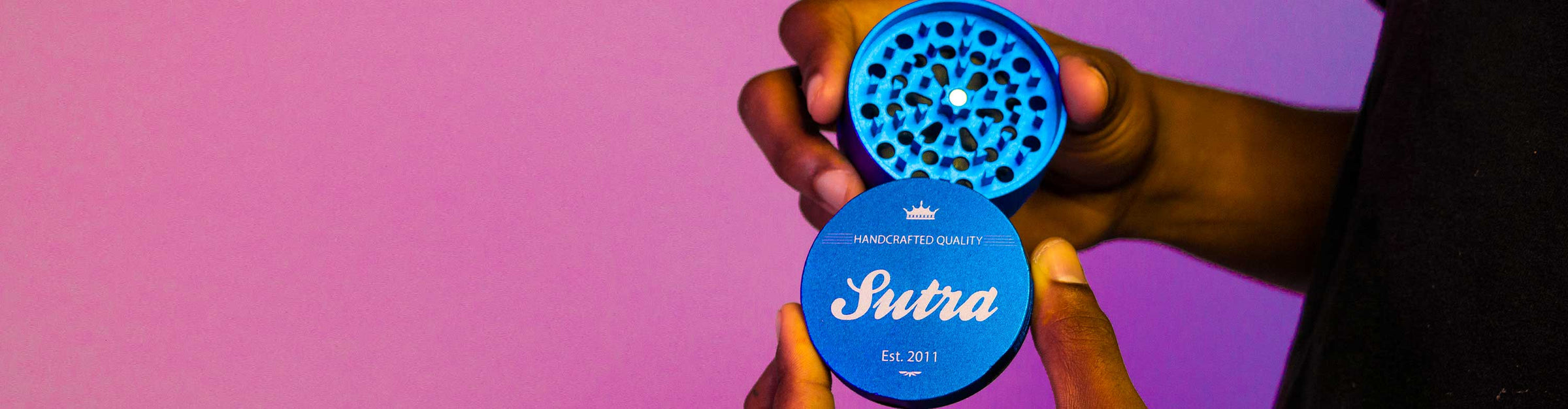 Man holding apart Sutra Grinder inside studio with purple and magenta lighting