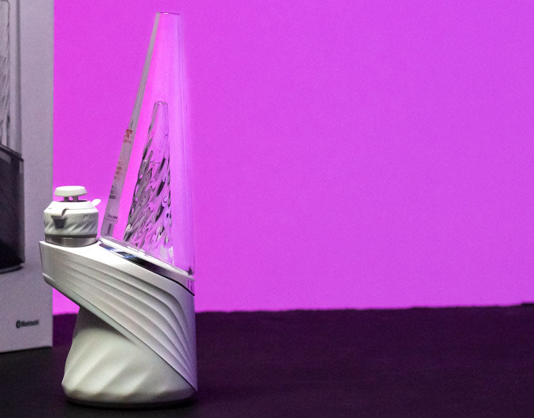 Puffco New Peak Pro standing on black table with purple background