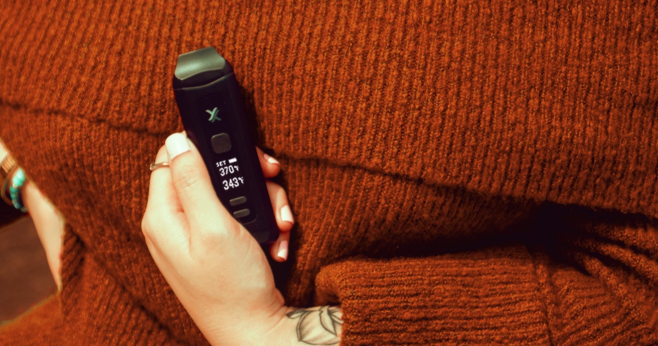 woman holding Exxus Mini Plus close to chest outside near park
