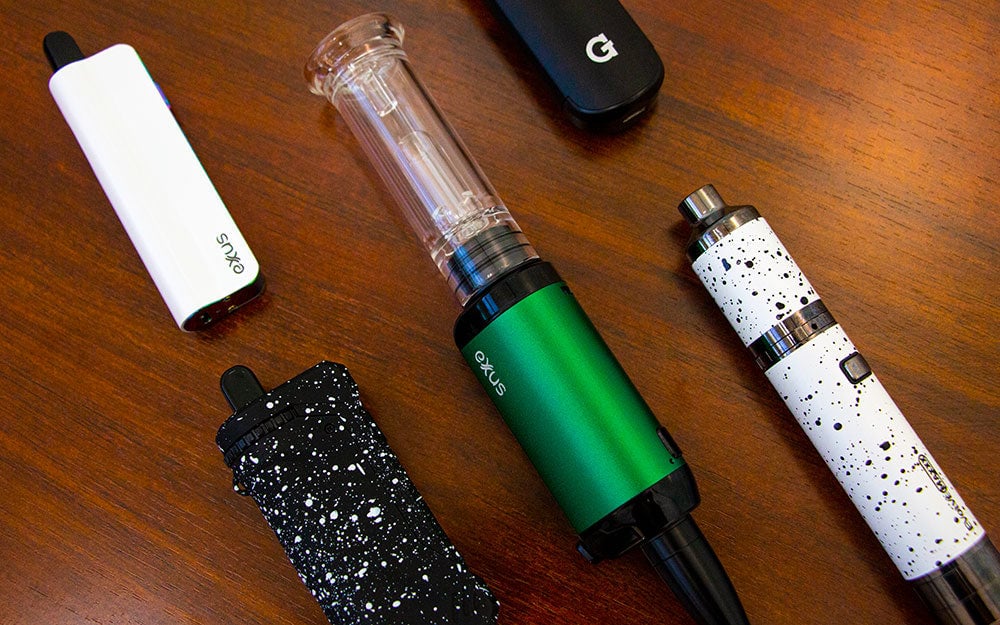 Vaporizer Devices laying in a row on wooden office desk in bright lighting