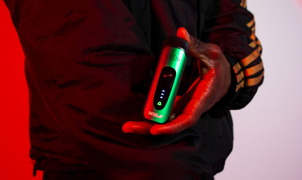 Person holding a WULF Next vaporizer under red lighting