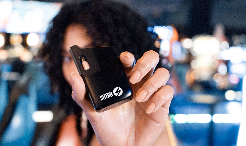 Person holding a black Sutra vaporizer in a shop