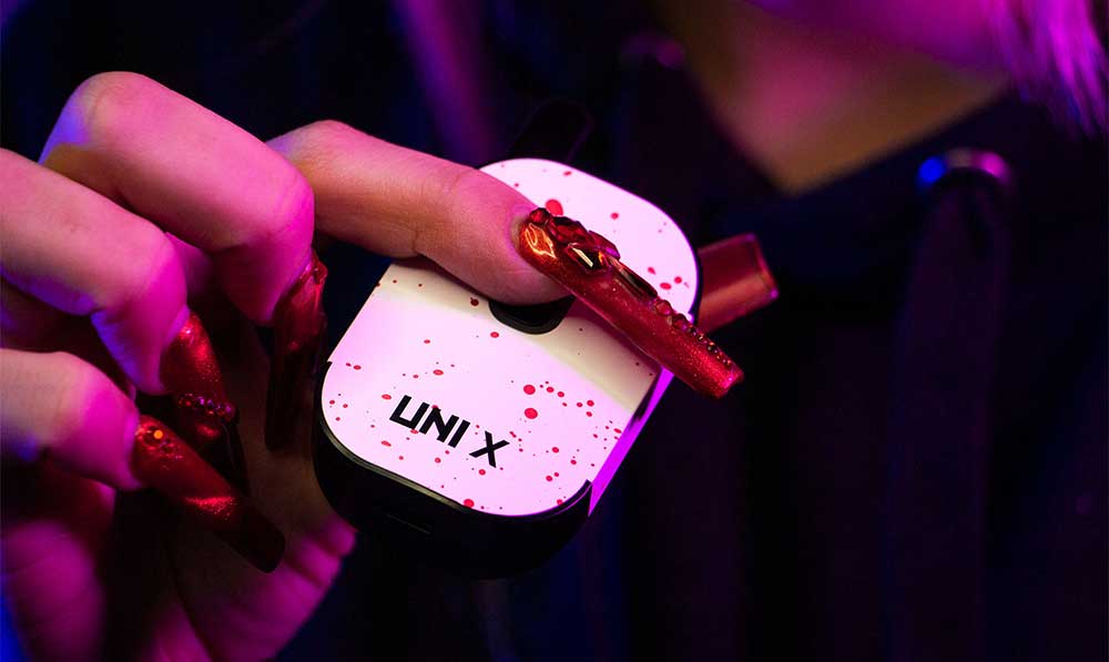 Hand holding a pink and white WULF Uni X 510 thread battery
