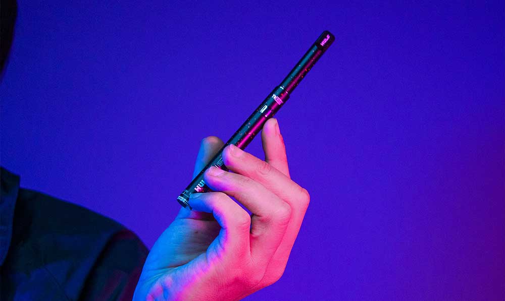 Hand holding a WULF Ari Slim concentrate straw against a purple background