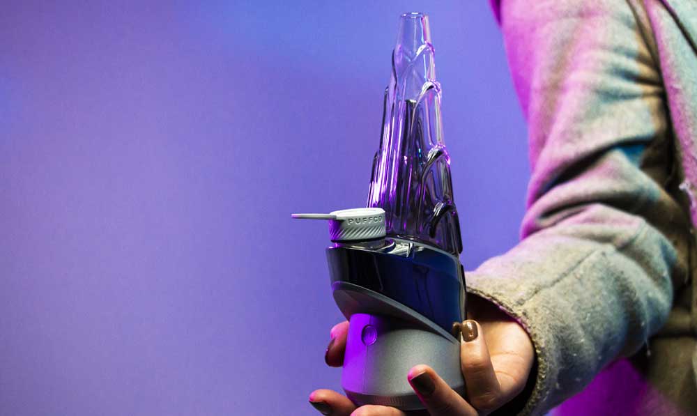 Hands holding a purple Puffco Peak Pro Guardian electronic rig