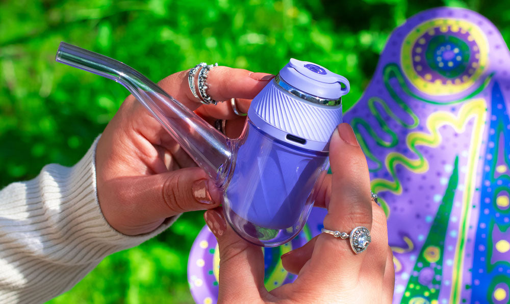 Woman holding Puffco Proxy Bloom over lavender butterfly statue