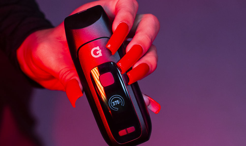 Woman holding G Pen Dash Plus in front of lavender background under red lighting