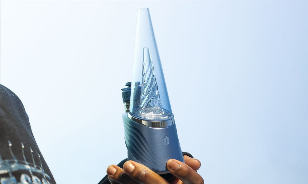 Man holding Puffco Peak Pro Storm in front of blue studio background