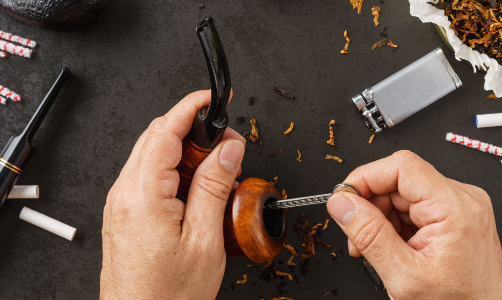 Man cleaning hand pipe with cleaning tool on work desk