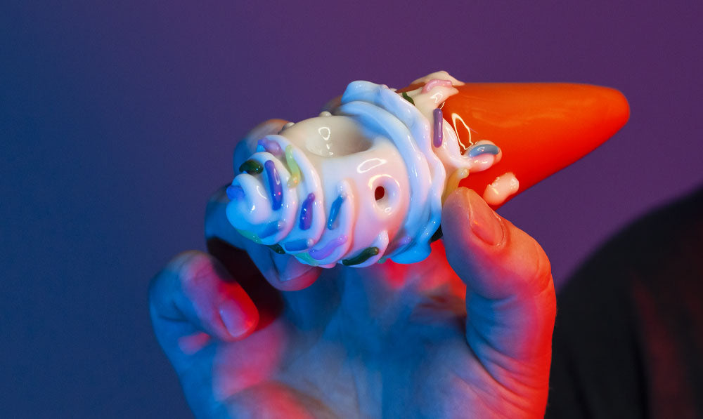 Man holding Empire Glassworks Sprinkle Spoon Pipe in front of purple studio background