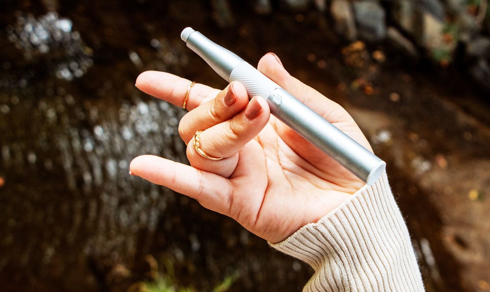 Woman holding Puffco Plus above a creek