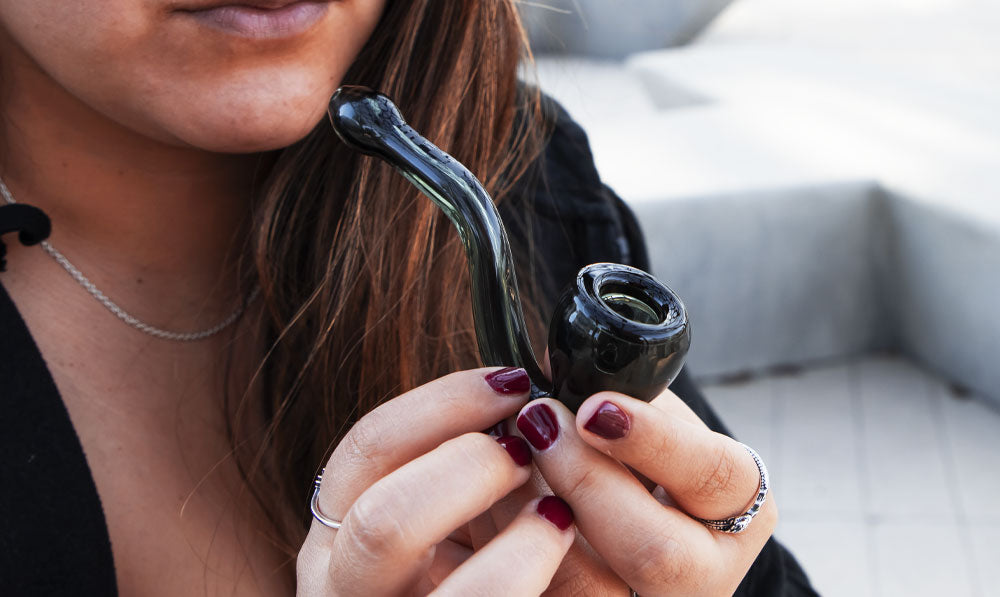 Person holding a WULF Smoke Curv hand pipe at a park