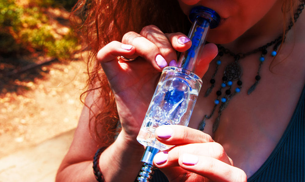 Woman using Wulf Nova Nectar Collector in forest clearing