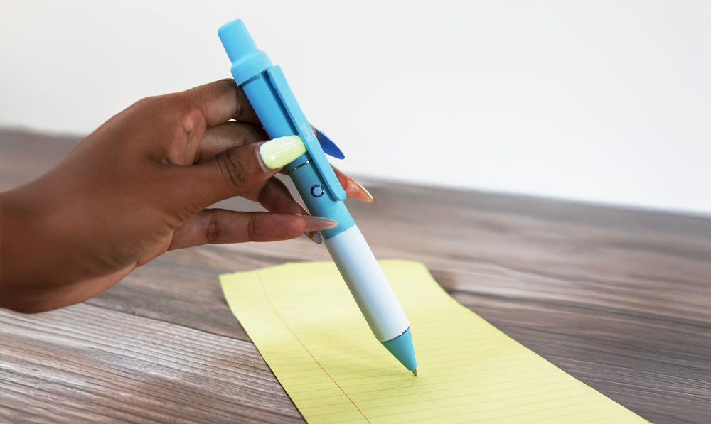 Woman's hand holding Smyle Penjamin Cart Pen over a sheet of notebook paper
