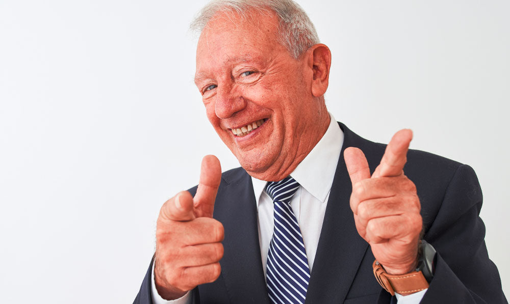 Person in a suit smiling and pointing at the camera