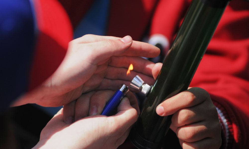 Friend lighting a water pipe for another person