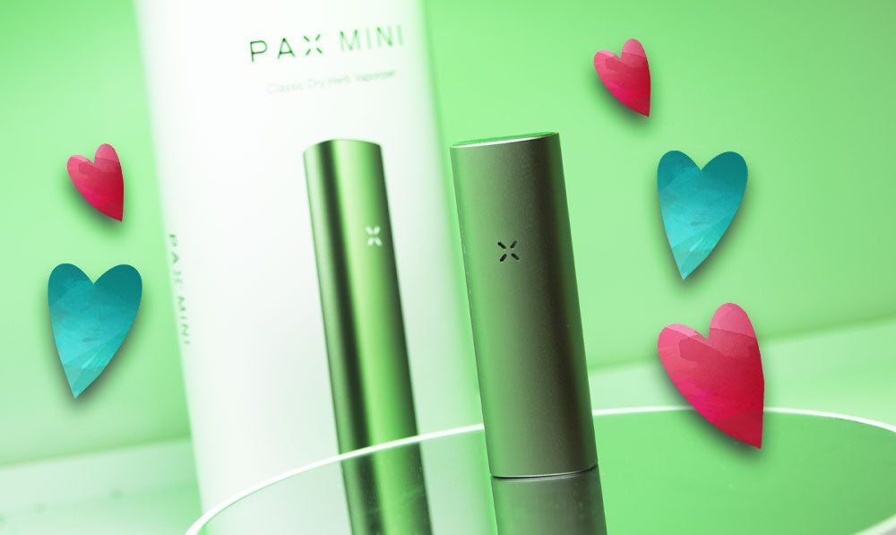 PAX Mini 2 on green reflective surface with hearts nearby