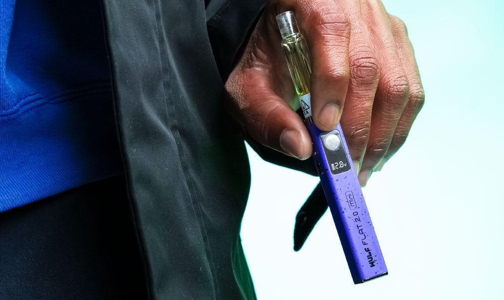 Man holding Wulf Flat Mini 2.0 in front of teal studio background