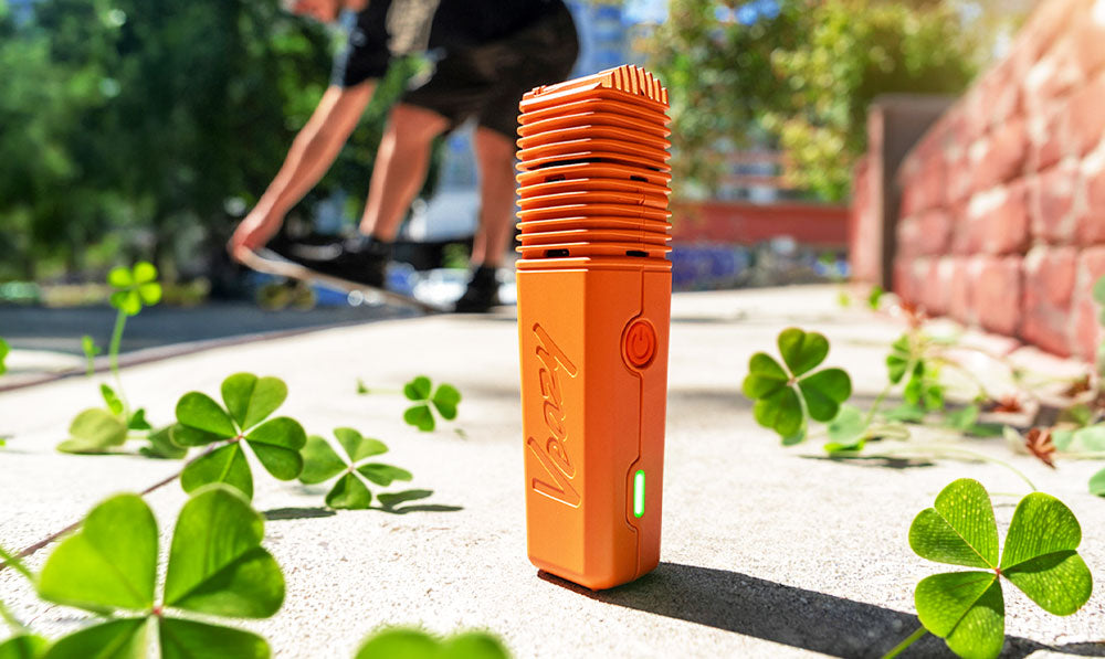 Storz & Bickel Veazy on walkway with four leaf clovers scattered nearby