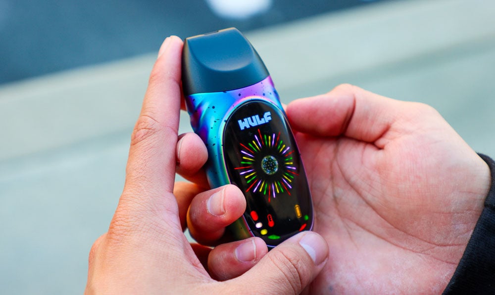 Man holding Wulf Mods Faze Dry Herb Vaporizer in hands on blurry lifestyle background