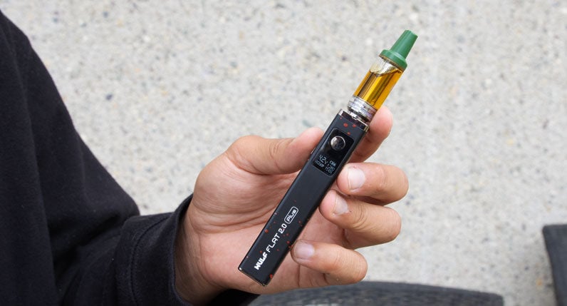Person holding a black WULF Flat Plus 2.0 510 thread battery with a cartridge attached