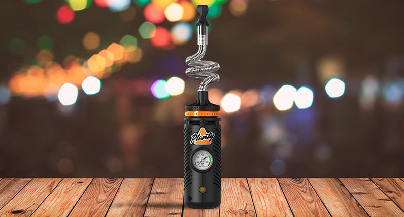 Storz and Bickel Plenty Vaporizer standing on wooden table with lights in background