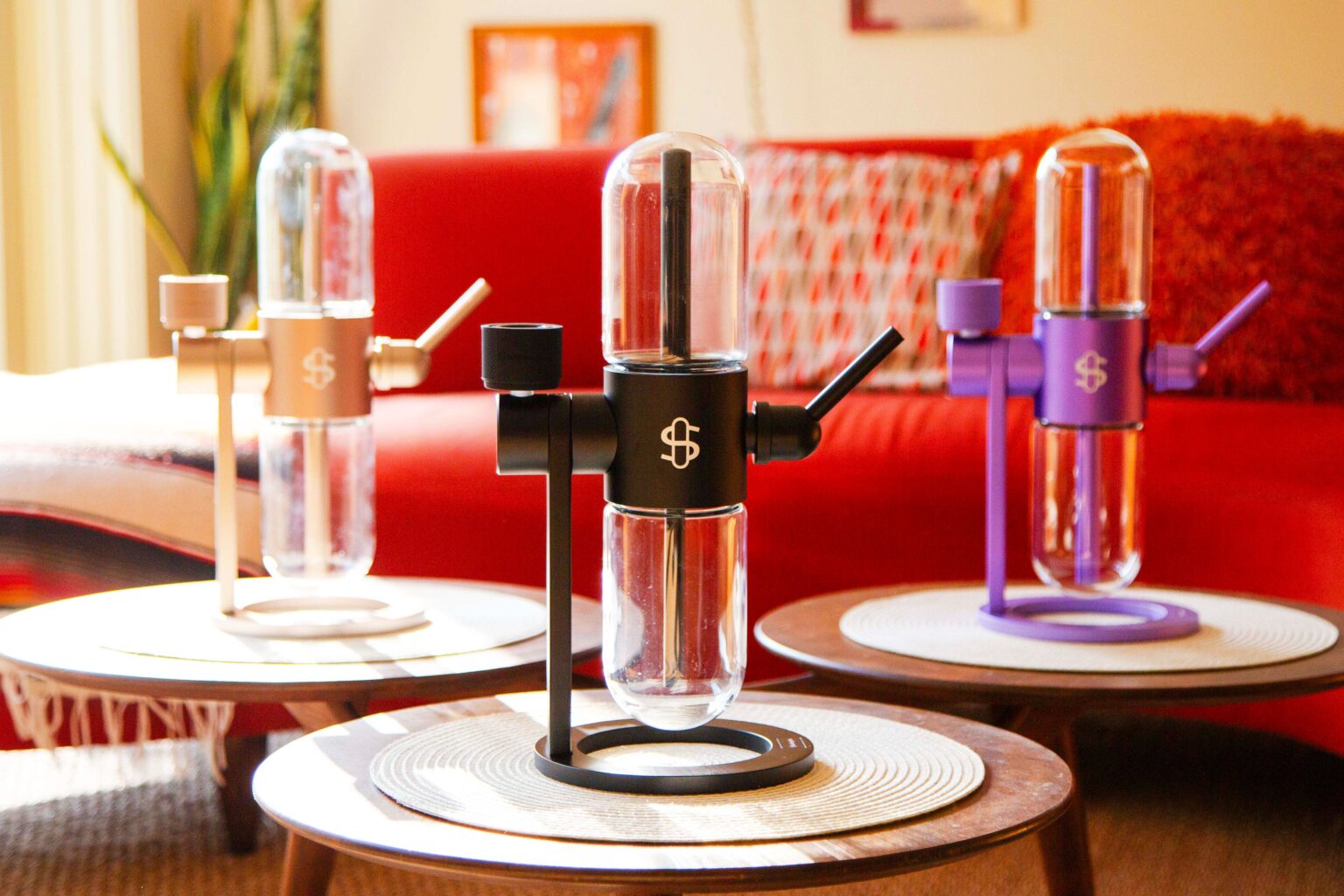 Stundenglass Gravity Infuser on a table with a red sofa and decorative items in the background