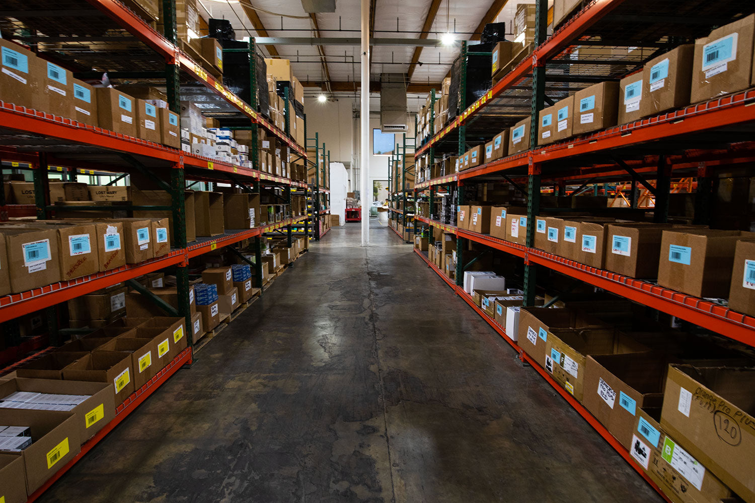 Warehouse aisle lined with orange racking stacked with labelled inventory boxes