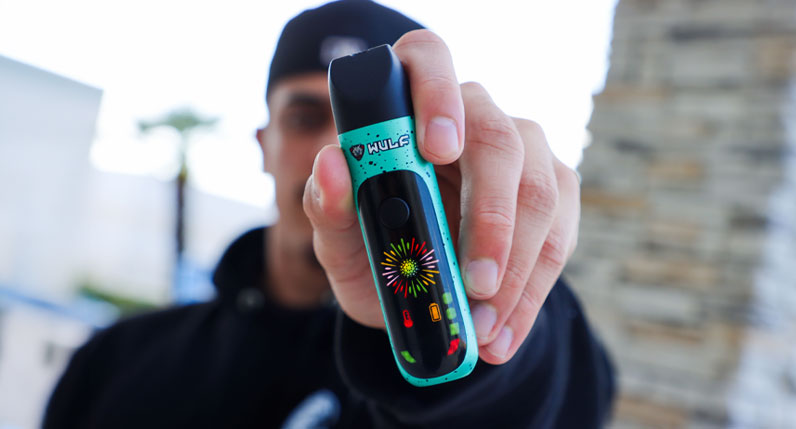 Person holding a teal WULF Budr portable concentrate vaporizer