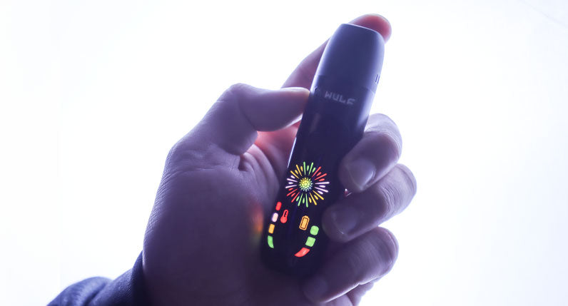 Hand holding a WULF Budr with its LED screen lit against a dark background