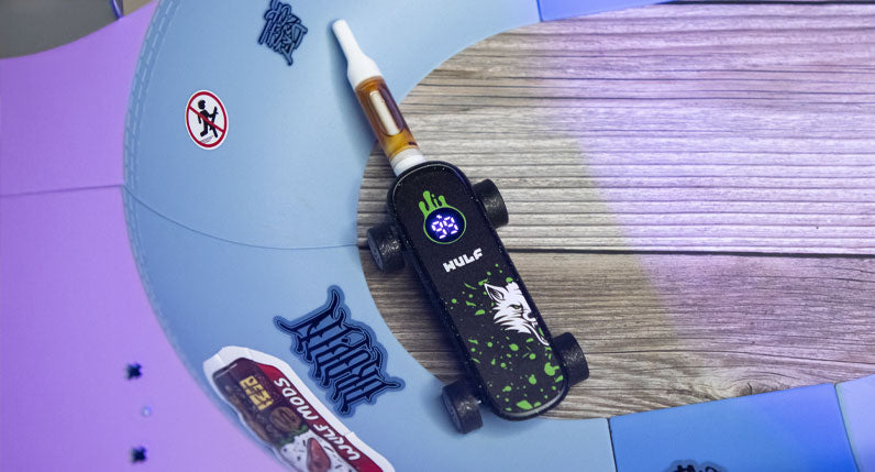WULF Deck skateboard shaped 510 thread battery on a wooden surface beside a skateboard