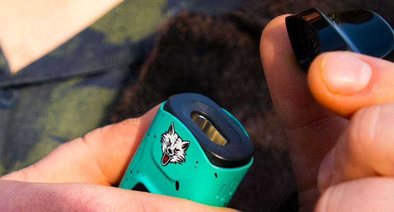 Hands holding a teal WULF Flex dual use vaporizer outdoors