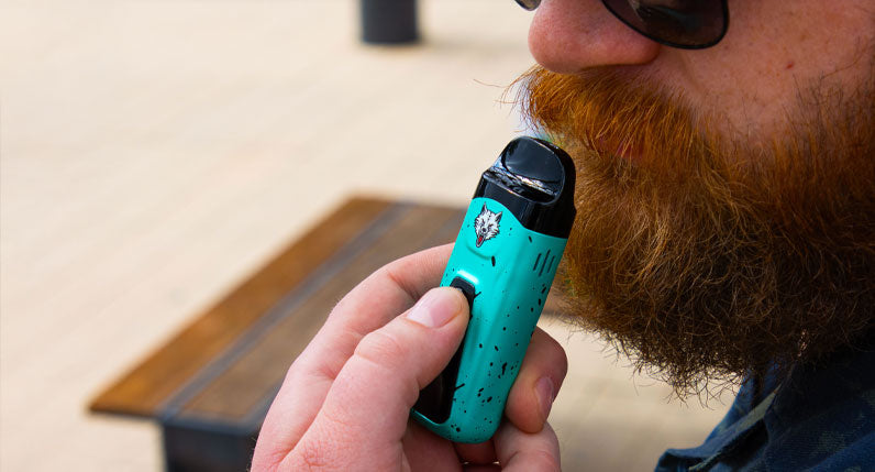 Person holding a teal WULF Flex dual use vaporizer