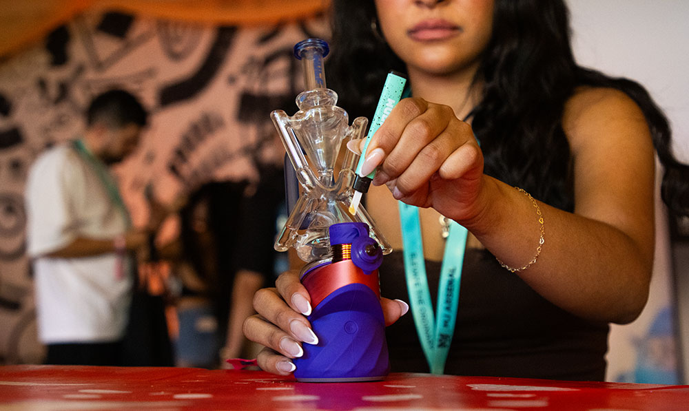 woman using the Puffco Plasma Peak with Wulf Web Glass Attachment and holding Wulf Slyce hot knife at Puffcon VIP Lounge